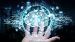 La imagen muestra una representación artística de un cerebro humano en el centro, rodeado de circuitos y patrones digitales que irradian desde él, ilustrando una fusión de tecnología y mente humana. La mano de una persona sostiene este cerebro tecnológico, sugiriendo un concepto de control o manipulación. El fondo oscuro y los destellos de luz azulada añaden un aura de misterio y futurismo. Esta imagen podría simbolizar temas como la inteligencia artificial, la neurotecnología o el avance de la ciencia en la comprensión y mejora del cerebro humano.